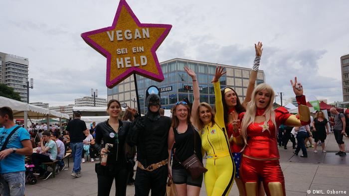 People dressed as superheroes hold a star-shaped sign saying, Vegan: Be a hero (DW/L. Osborne)